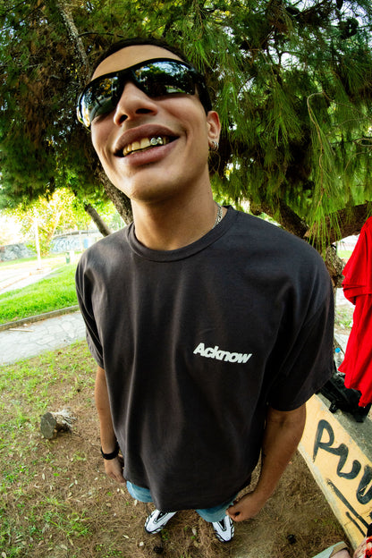 Model in sunglasses wearing the grey Acknow Make Them Know T-shirt