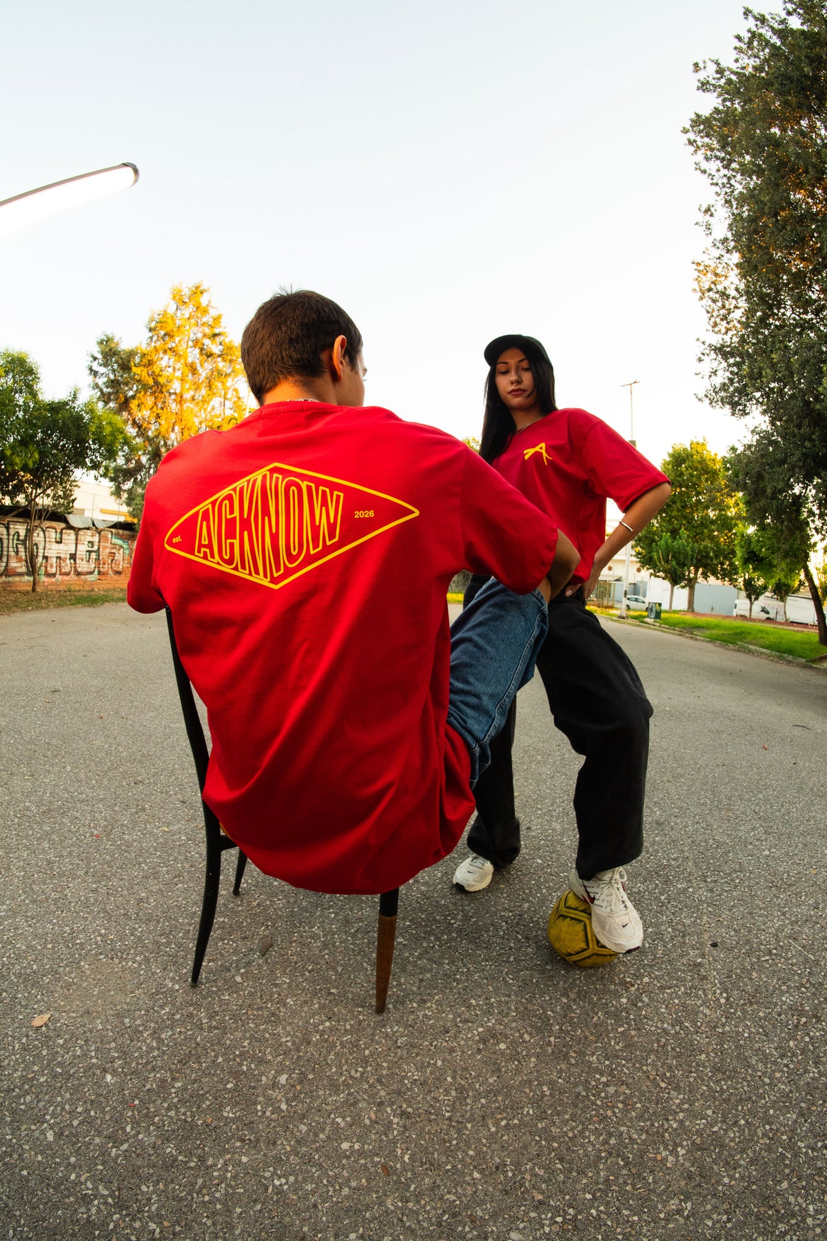 Models wearing the red Acknow Alfa T-shirt, showing the back graphic