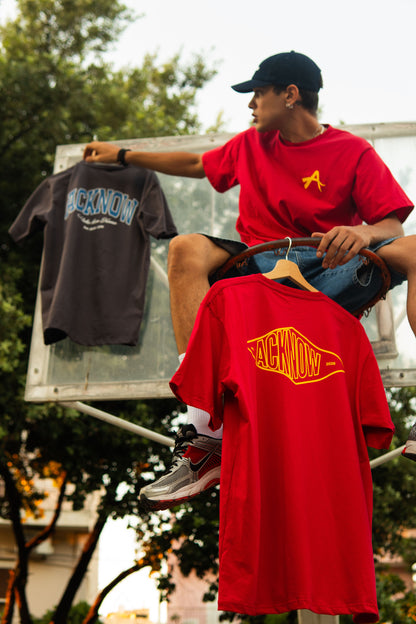 Model holding the red Acknow Alfa T-shirt and the Make Them Know T-shirt