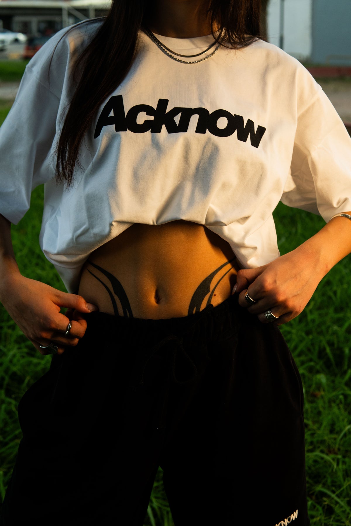 Model wearing the Acknow Classic Logo Tee in white with black trousers