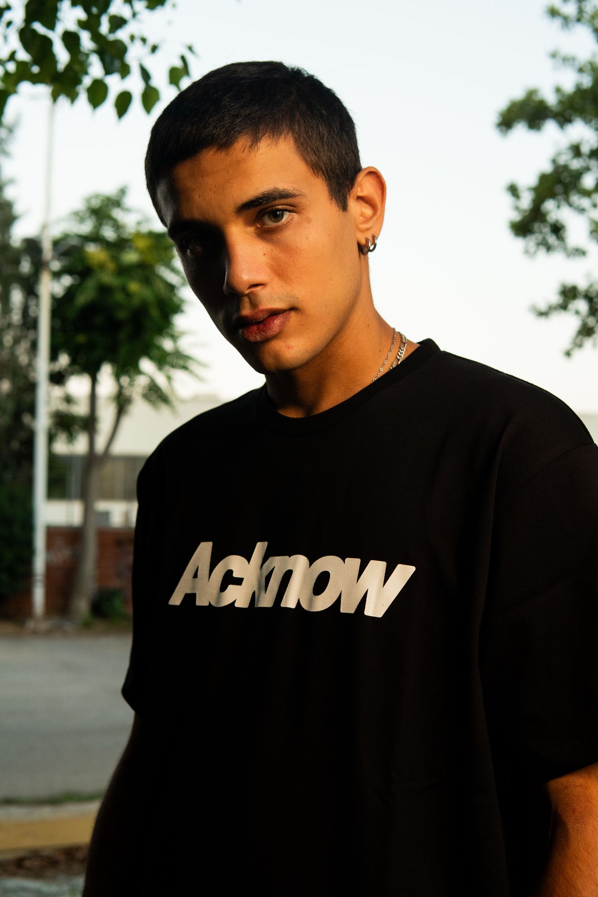 Model wearing the Acknow Classic Logo Tee in black outdoors