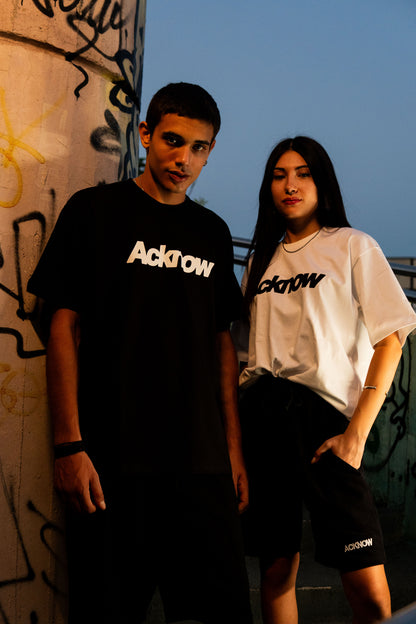 Two models wearing the Acknow Classic Logo Tee in black and in white